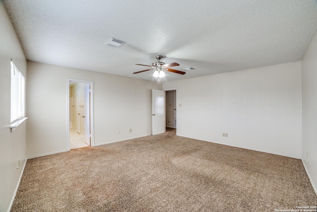 carpeted empty room with a textured ceiling, baseboards, visible vents, and a ceiling fan