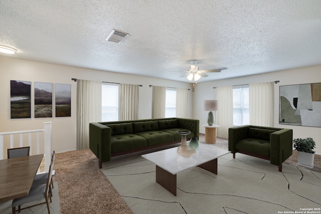 living area featuring visible vents, ceiling fan, light carpet, and a textured ceiling