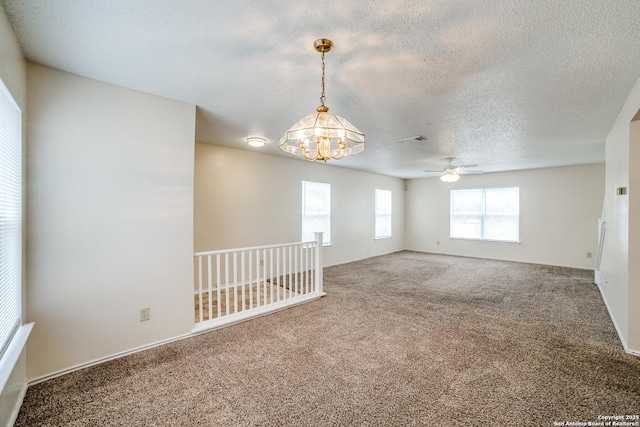 carpeted empty room featuring visible vents, a chandelier, and a textured ceiling