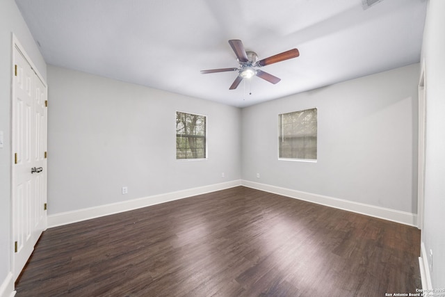 unfurnished room featuring dark wood-style flooring, a ceiling fan, and baseboards