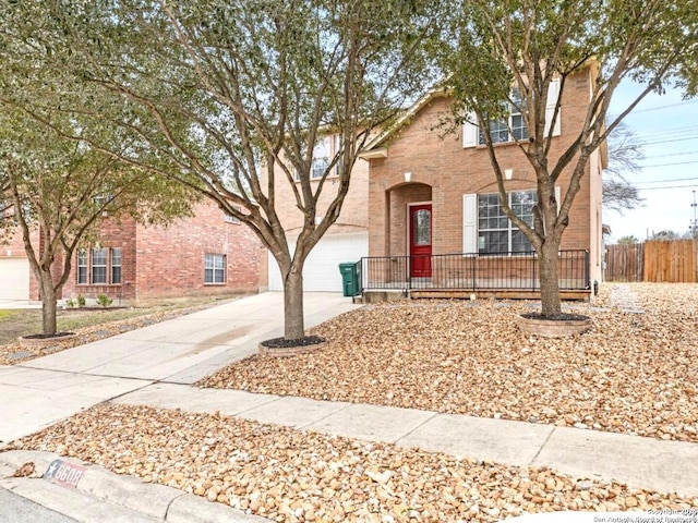 traditional-style home featuring concrete driveway, brick siding, and fence