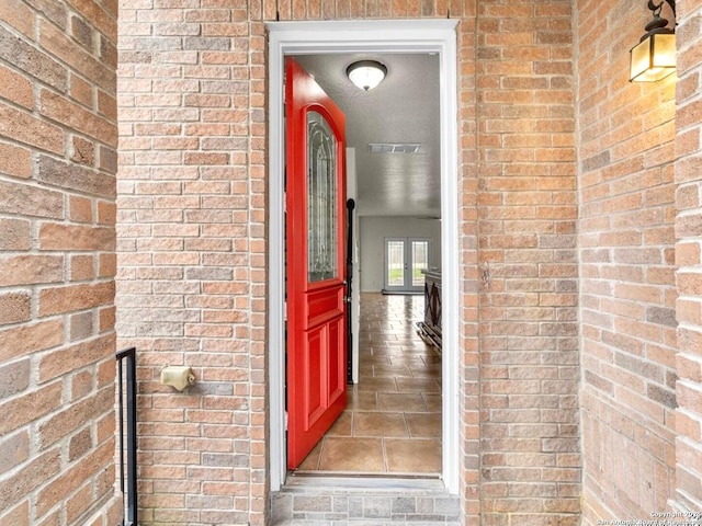 view of exterior entry with brick siding and visible vents