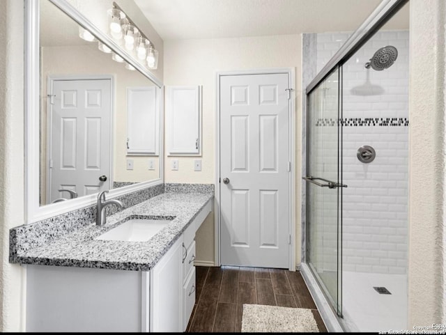 bathroom featuring a stall shower, wood tiled floor, and vanity