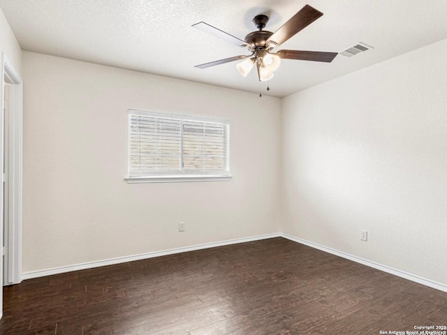 unfurnished room featuring dark wood-style floors, ceiling fan, visible vents, and baseboards