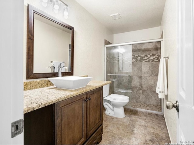 bathroom featuring a stall shower, visible vents, toilet, a textured ceiling, and vanity