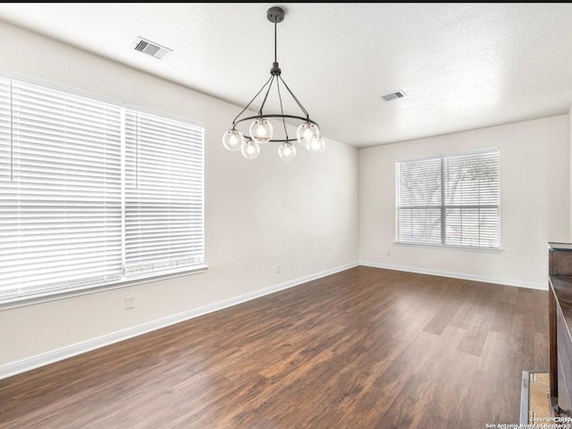 interior space featuring visible vents, dark wood finished floors, a textured ceiling, and a notable chandelier