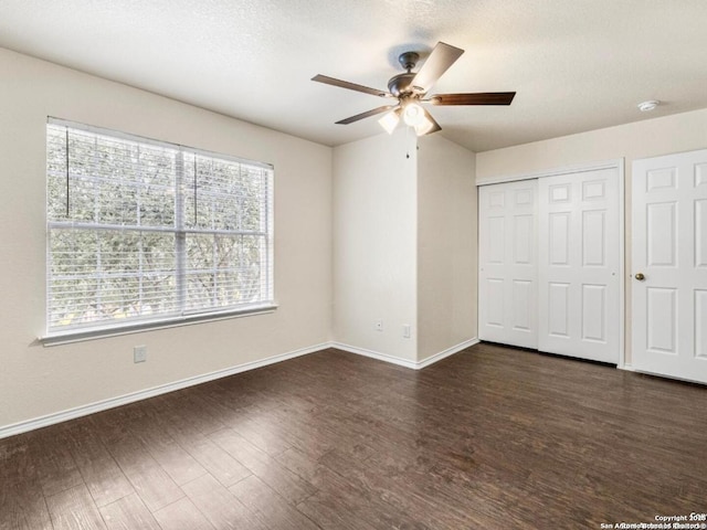 unfurnished bedroom featuring dark wood-style floors, a textured ceiling, baseboards, and a closet