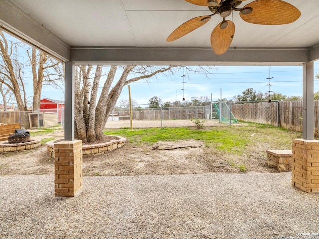 view of yard featuring a fenced backyard, ceiling fan, and a fire pit