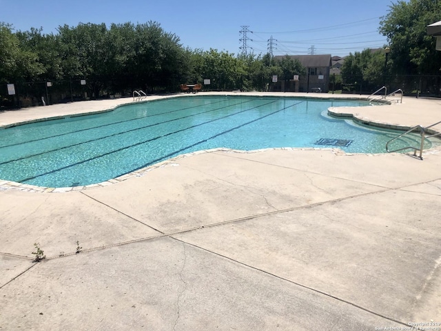 community pool with a patio and fence