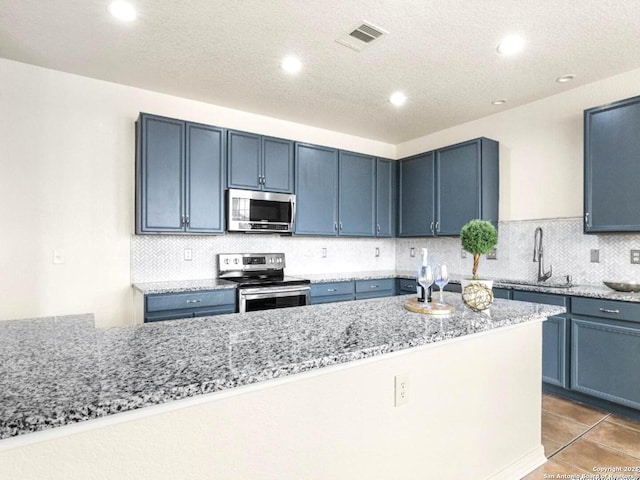 kitchen with light stone counters, a sink, visible vents, appliances with stainless steel finishes, and decorative backsplash