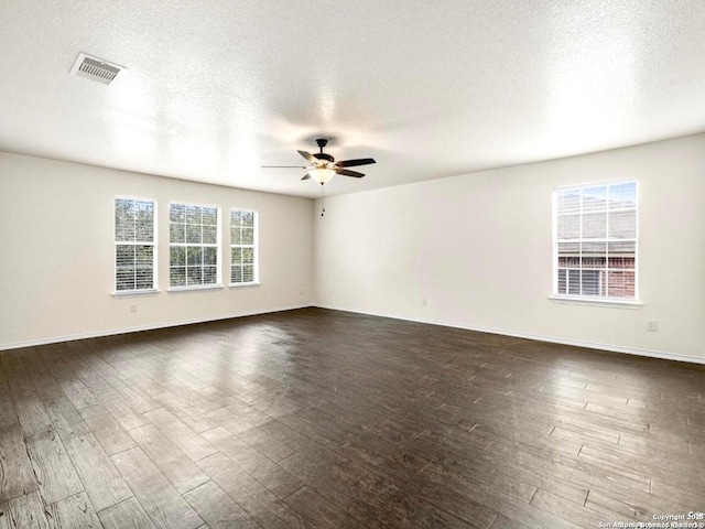 unfurnished room with ceiling fan, a textured ceiling, dark wood-style flooring, visible vents, and baseboards