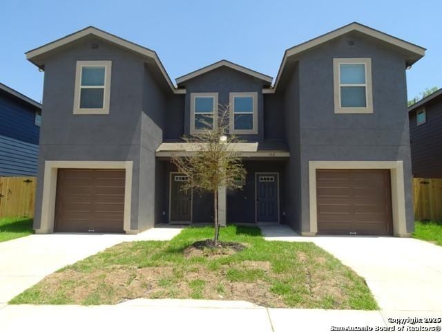 traditional home featuring an attached garage, fence, concrete driveway, and stucco siding