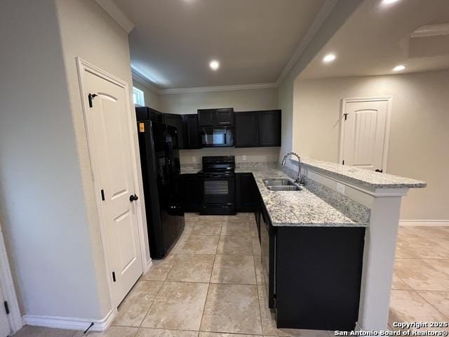 kitchen with light stone counters, dark cabinets, a peninsula, black appliances, and a sink