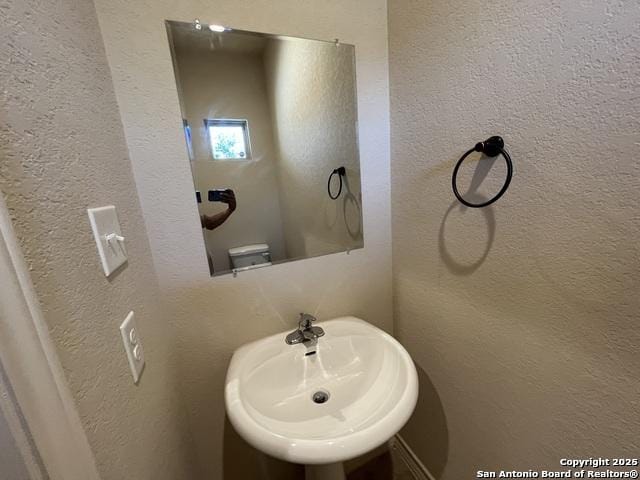 bathroom with a textured wall and a sink