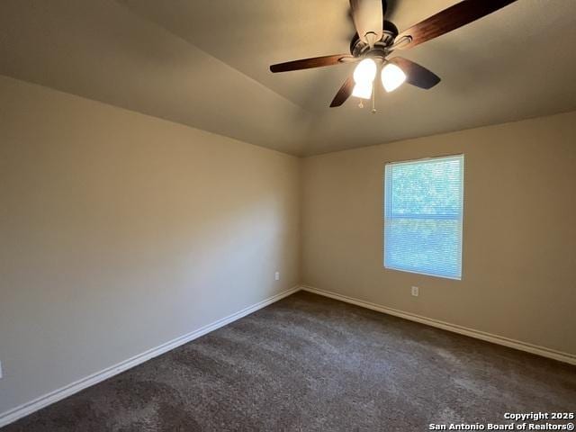 unfurnished room with ceiling fan, vaulted ceiling, dark carpet, and baseboards