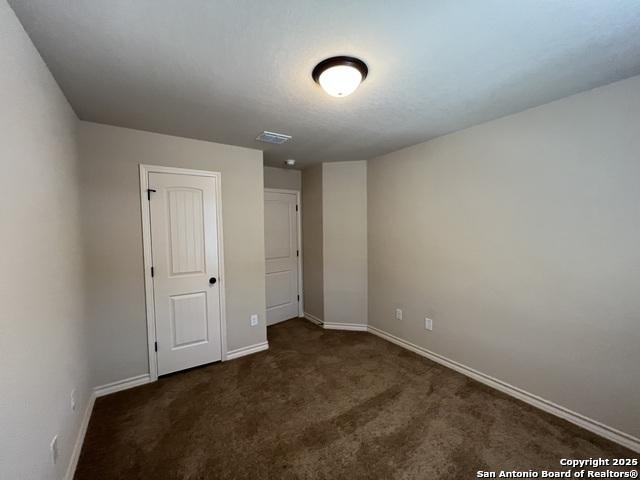 spare room with baseboards, visible vents, and dark carpet