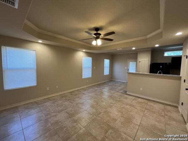 unfurnished room with crown molding, a raised ceiling, visible vents, ceiling fan, and baseboards