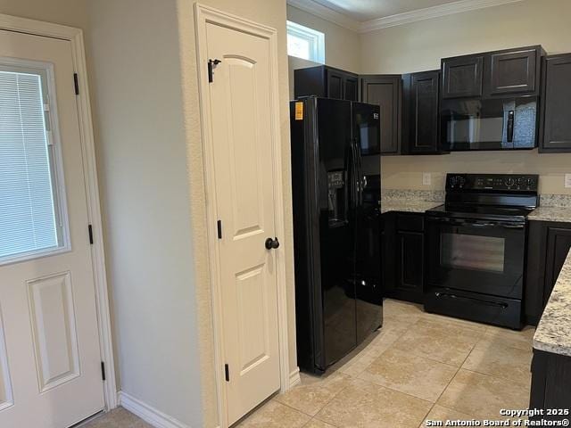 kitchen featuring light tile patterned floors, light stone counters, dark cabinets, crown molding, and black appliances