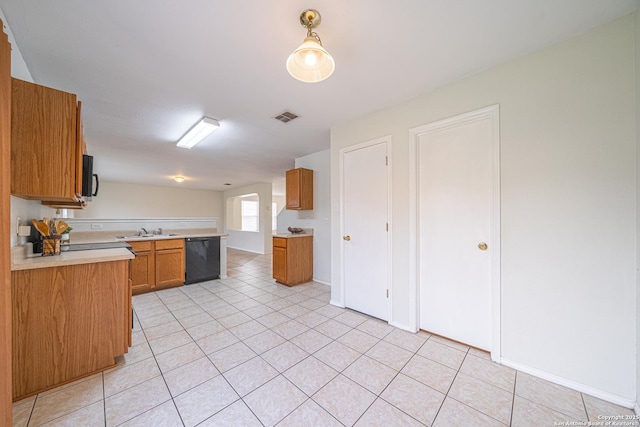 kitchen with light tile patterned floors, a sink, light countertops, brown cabinets, and black appliances