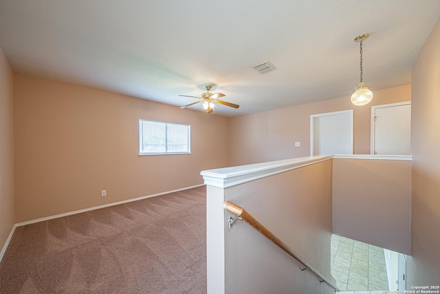 hallway featuring carpet, baseboards, visible vents, and an upstairs landing