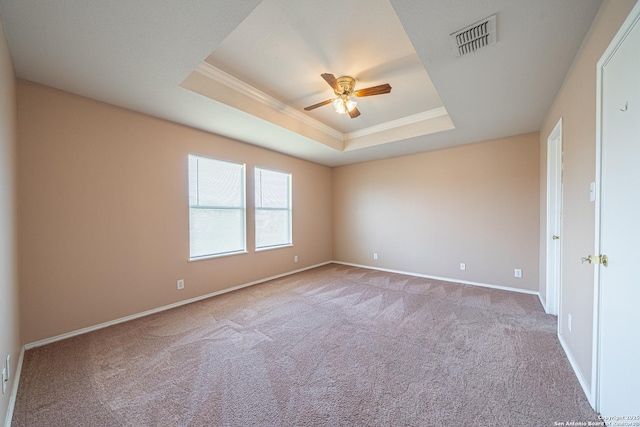 spare room featuring a raised ceiling, visible vents, crown molding, and light carpet