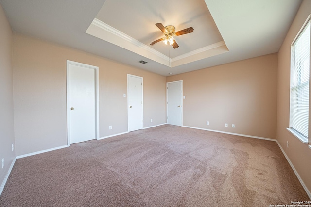 unfurnished bedroom with baseboards, visible vents, ornamental molding, a tray ceiling, and carpet flooring