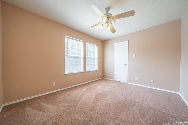 carpeted spare room featuring ceiling fan and baseboards