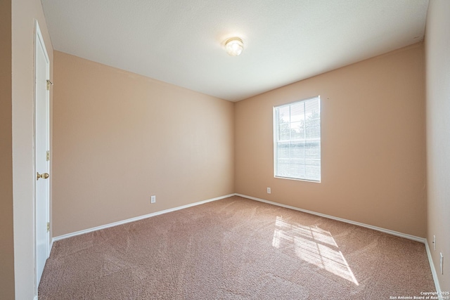 carpeted spare room featuring baseboards