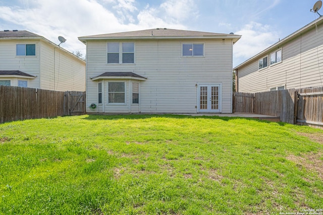 rear view of property featuring a yard, french doors, and a fenced backyard