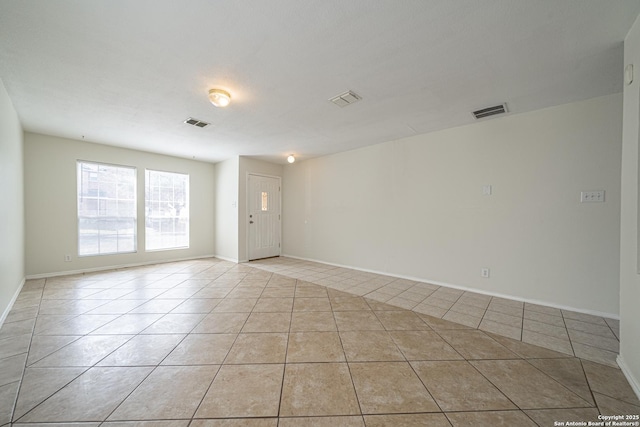 spare room featuring light tile patterned floors, visible vents, and baseboards