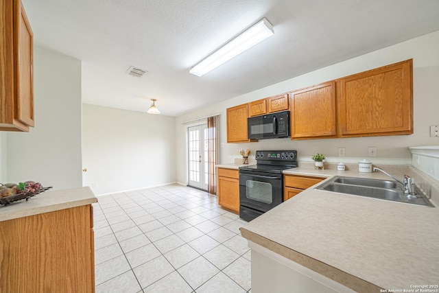 kitchen featuring light countertops, visible vents, brown cabinetry, a sink, and black appliances