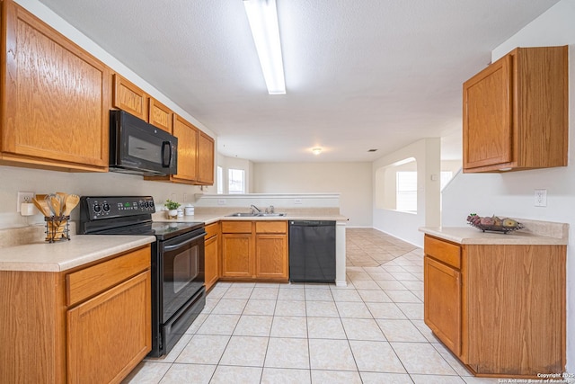 kitchen with black appliances, light countertops, a sink, and light tile patterned flooring