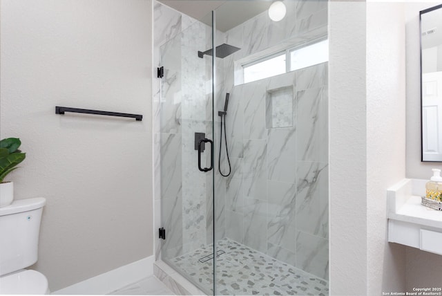 bathroom with toilet, a textured wall, a marble finish shower, and vanity