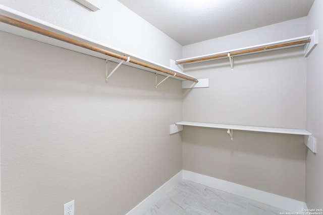 walk in closet featuring marble finish floor