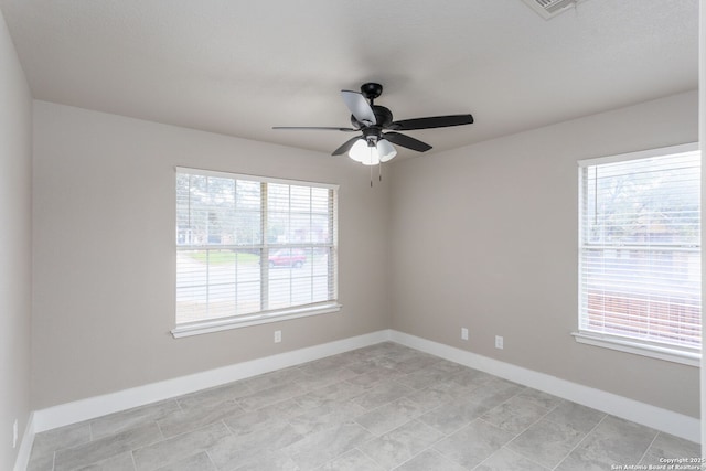 unfurnished room featuring a ceiling fan, a wealth of natural light, visible vents, and baseboards