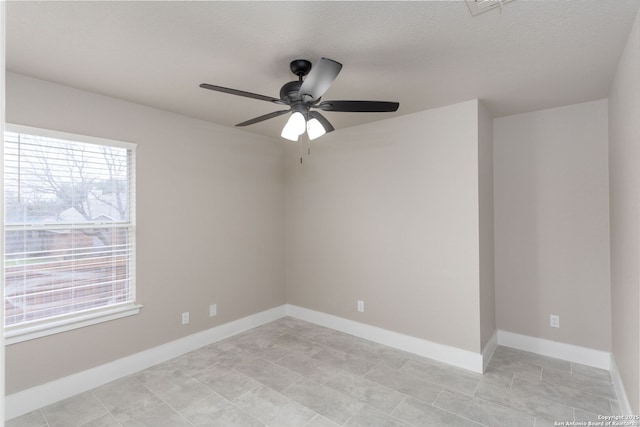 spare room featuring baseboards, ceiling fan, a textured ceiling, and a healthy amount of sunlight