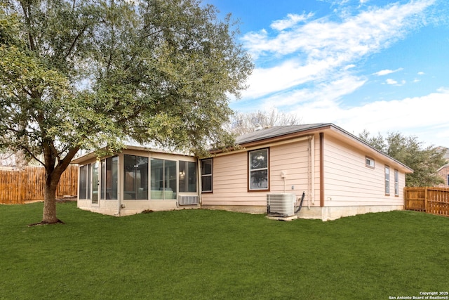 back of house with central AC unit, a lawn, a fenced backyard, and a sunroom