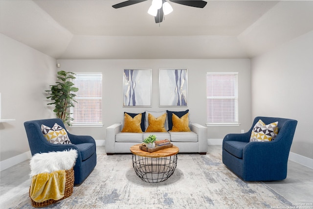 living room featuring baseboards, a tray ceiling, and a ceiling fan