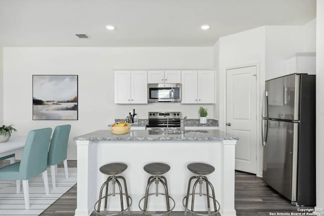 kitchen with visible vents, appliances with stainless steel finishes, stone counters, and white cabinetry