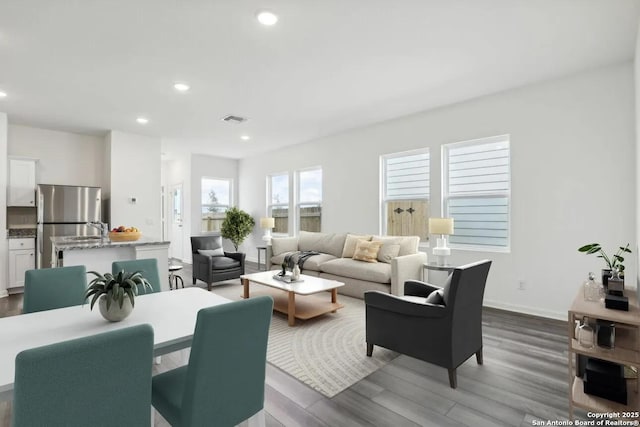 living room featuring recessed lighting, visible vents, baseboards, and wood finished floors