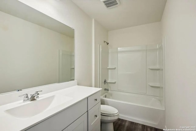 bathroom with visible vents, toilet, wood finished floors,  shower combination, and vanity