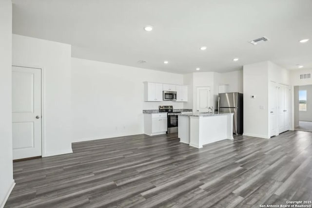 kitchen featuring dark wood-style flooring, visible vents, appliances with stainless steel finishes, a kitchen island with sink, and white cabinetry