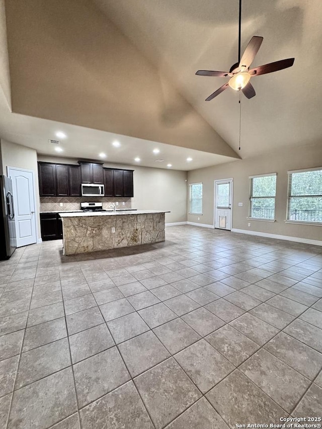 unfurnished living room featuring light tile patterned floors, recessed lighting, ceiling fan, high vaulted ceiling, and baseboards