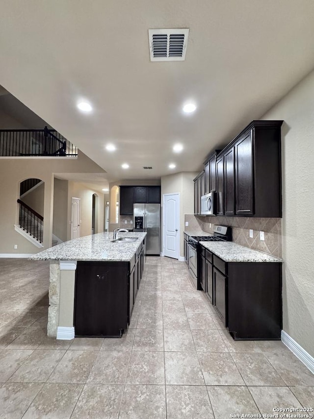 kitchen with a center island with sink, tasteful backsplash, visible vents, appliances with stainless steel finishes, and light stone countertops