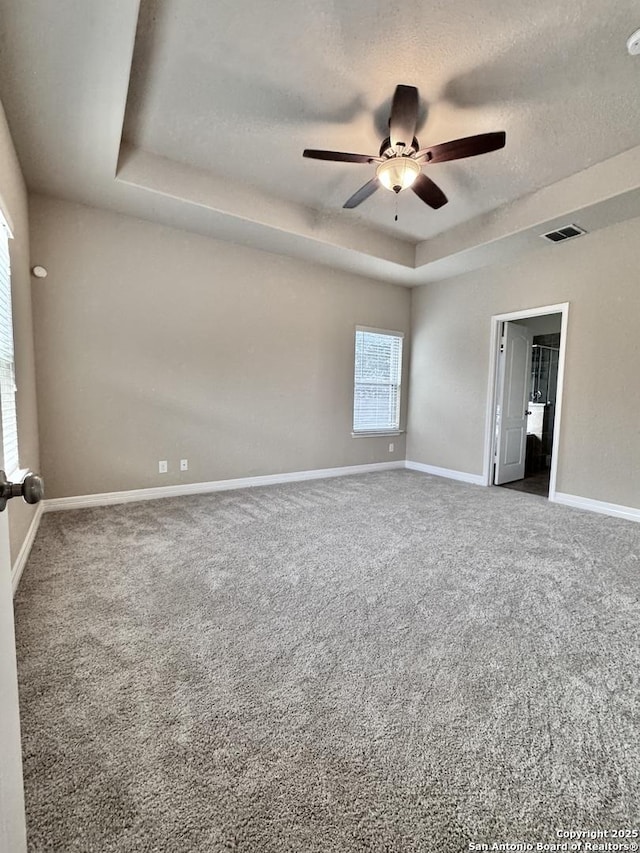 spare room with visible vents, a raised ceiling, baseboards, carpet, and a textured ceiling