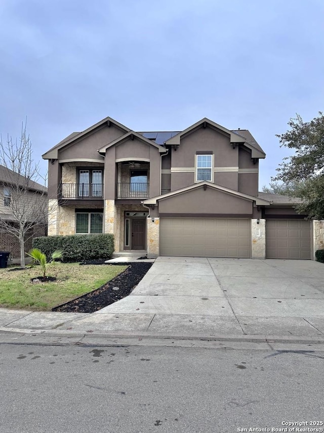 view of front of property featuring solar panels, stucco siding, concrete driveway, a balcony, and stone siding