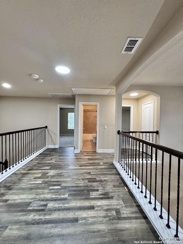 unfurnished room with visible vents, dark wood finished floors, a textured ceiling, and baseboards