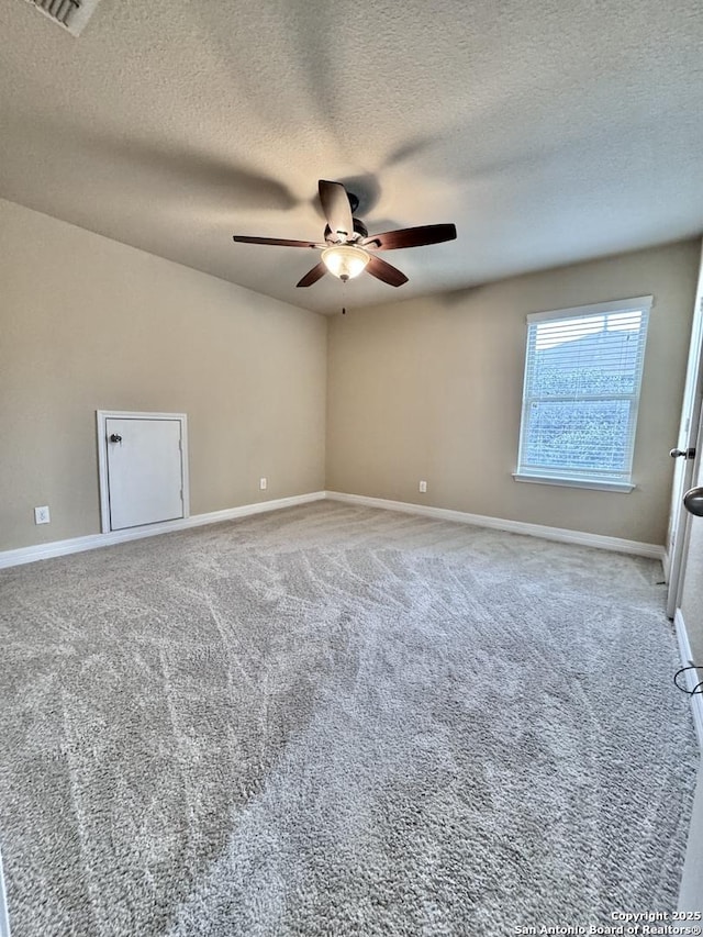 spare room with carpet floors, ceiling fan, baseboards, and a textured ceiling