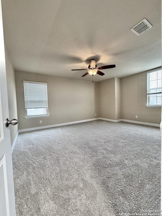 empty room with a ceiling fan, carpet, visible vents, and baseboards