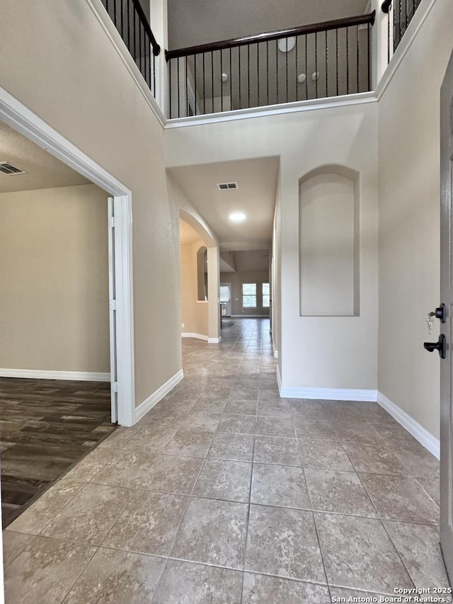 tiled entryway with arched walkways, visible vents, and baseboards